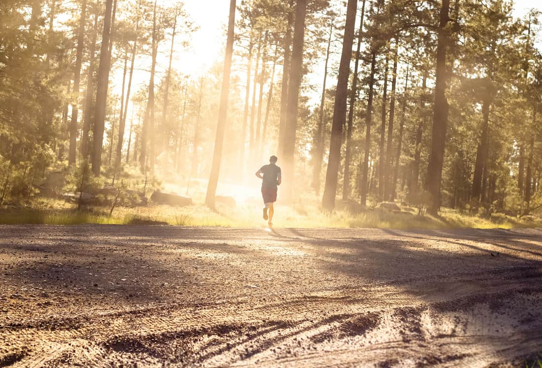 man running through a sunny forest